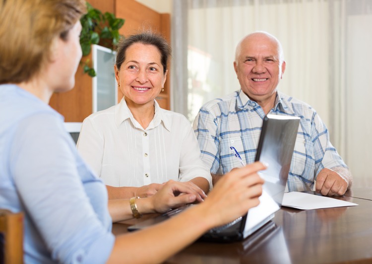 Smiling mature couple discussing for agent or employee of company at home